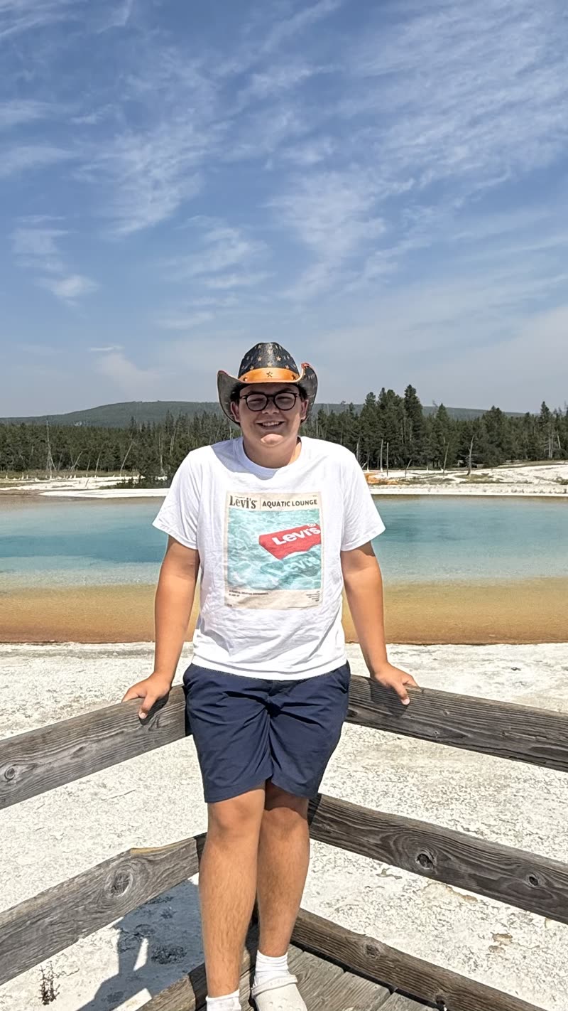 Jules, smiling, in a cowboy hat in front of a hot spring